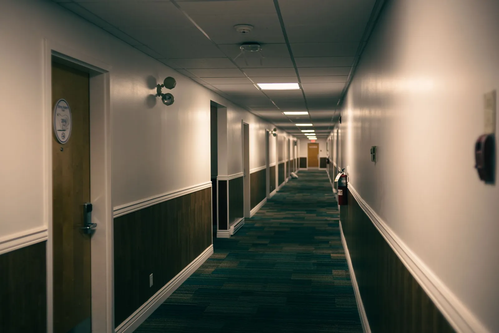 A carpeted hotel bedroom corridor with doors either side