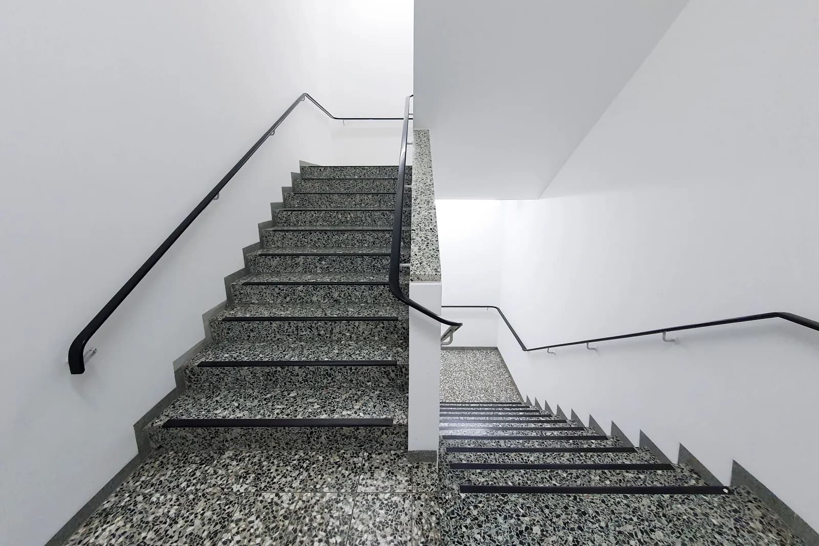 A clean white protected staircase with handrails in a commercial building